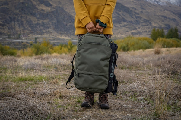 person in yellow jacket and black backpack walking on brown grass field during daytime