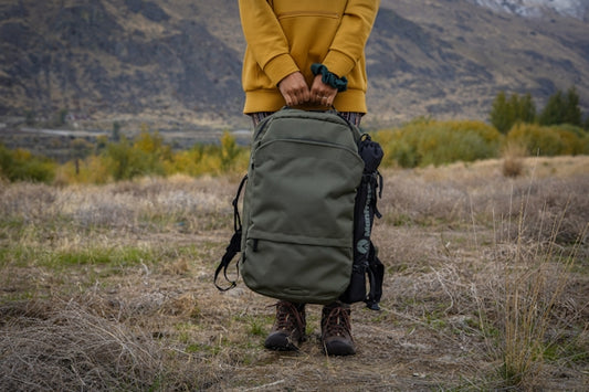 person in yellow jacket and black backpack walking on brown grass field during daytime