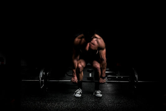 shirtless man lifting barbell in gym
