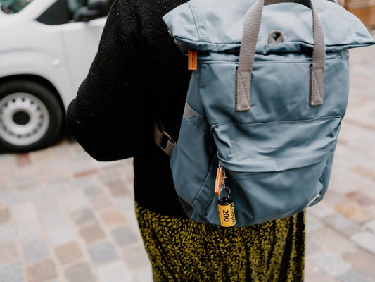 Person wearing a blue backpack with a yellow tag.