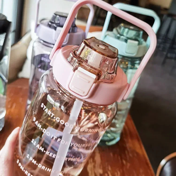 Valour Fit 2L motivational sports water bottle with time marker, clear plastic design, featuring measurement lines and a flip-top lid.